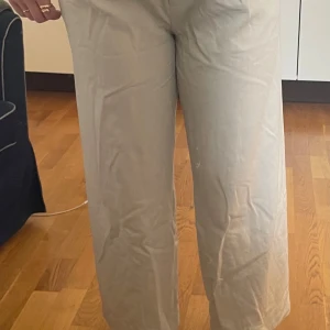 Beiga vida kostymbyxor - Snygga beiga kostymbyxor med rak och vid passform.💞 Byxorna har hög midja och är tillverkade i ett mjukt bomullsmaterial. Perfekta för en clean och stilren look, matcha med en enkel topp eller skjorta!💞💞