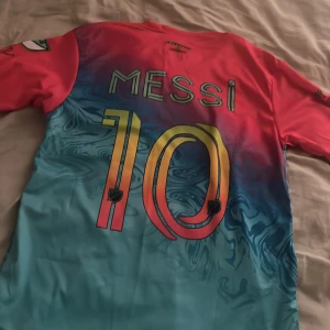Inter Miami Messi tröja Adidas 152 - Säljer en fet Inter Miami fotbollströja från Adidas med Messi och nummer 10 på ryggen. Tröjan har coolt mönster i rosa och blått, klubbmärke på bröstet och sponsortryck framtill. Gjord i lätt och skönt material, perfekt för dig som älskar fotboll och Messi.