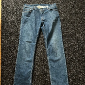  Acne Studios jeans - Säljer ett par klassiska blå jeans från Acne Studios. Modellen har en rak passform med normal midja och är tillverkad i mjukt bomullsjeans. Snygg och enkel design med fem fickor och dragkedja. Perfekta för en clean och stilren look.