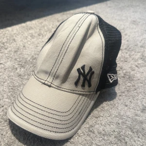 New Era Yankees truckerkeps svart/vit - Snygg truckerkeps från New Era med New York Yankees-logga framtill. Framsidan är vit med svarta broderade detaljer och baksidan är svart mesh för extra ventilation. Justerbar snapback baktill. 