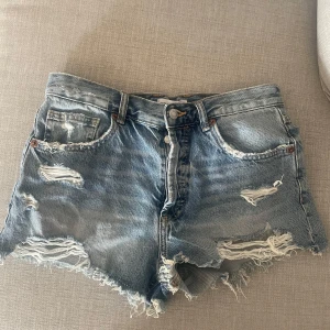 Jeansshorts - Blåa jeansshorts från Zara, storlek 38 med slitning. Säljs då de är för små, endast använd fåtal gånger