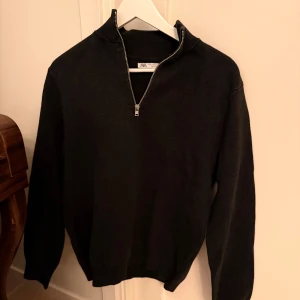Svart grön half zip tröja från Zara - Svart grön stickad tröja från Zara i storlek M med half zip-dragkedja och hög krage. Tröjan har lång ärm och ribbade muddar vid ärmslut och nederkant. Perfekt för lager-på-lager och chill stil.
