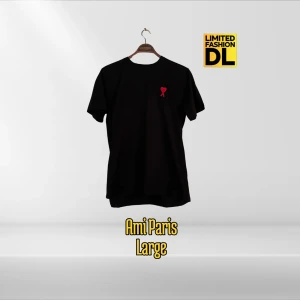 Svart t-shirt Ami Paris Large - Svart t-shirt från Ami Paris i storlek Large. Tillverkad i 100% bomull och har en klassisk passform med korta ärmar. På bröstet finns Ami Paris ikoniska röda hjärta-broderi som ger en clean och stilren vibe.