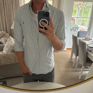Randig skjorta från Ralph Lauren M - Snygg slim fit skjorta från Ralph Lauren. Köpte i butik förra sommaren, väldigt sparsamt använd, inga defekter förutom lite annan färg inuti kragen(bild 4) men syns ABSOLUT INTE utifrån😊😊