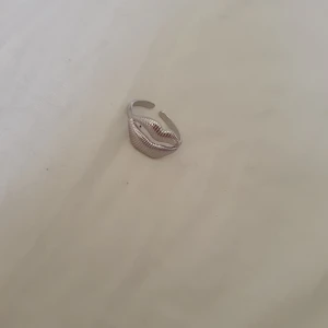 Silvrig ring med läppformad design - Cool silvrig ring med en unik läppformad front och räfflad yta som ger extra edge. Justerbar storlek så den passar de flesta fingrar. Perfekt accessoar för dig som vill sticka ut med något annorlunda och trendigt.