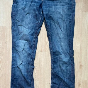 Blåa jeansbyxor  - Snygga blå jeansbyxor. Klassisk femficksdesign med raka ben och normal passform. Jeansen har en cool tvättad look och detaljerade sömmar. Perfekta för dig som gillar en avslappnad stil med lite edge.