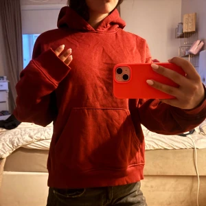 Röd hoodie med huva och ficka - Säljer en röd hoodie från Gina tricot med stor huva och magficka. Tröjan har en loose passform och långa ärmar, perfekt för chill dagar. Materialet känns mjukt. Enkel och stilren design utan tryck eller logga.