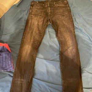 Svarta Jack & Jones jeans byxor - Säljer ett par svarta slim fit jeans från Jack & Jones, modell Glenn. Jeansen har klassisk femficksdesign, normal midja och raka ben. Materialet är stretchigt jeans och färgen är tvättad svart med lätt slitning för en cool look.
