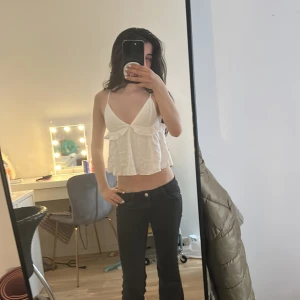 Vit volangig linnetopp med smala axelband - Supersöt vit linnetopp med smala axelband och volangdetalj framtill. Toppen är croppad och har en luftig passform med v-ringning.