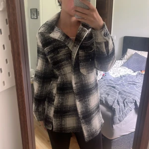 Rutig Kappa XS - Snygg och trendig overshirt i svartvitt rutigt mönster. Jackan har klassisk krage, knäppning framtill och två bröstfickor. Perfekt för lager-på-lager och ger en cool vibe till din outfit. Passar dig som gillar en avslappnad men stilsäker look.