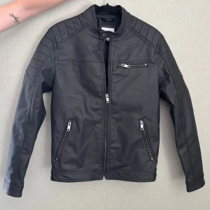 Svart skinnjacka från Jack & Jones - Säljer en snygg skinnjacka i storlek M från Jack & Jones (herr). Jackan är endast använd en gång och säljs då den inte kommer till användning. Inga defekter och i princip nyskick! Bara att skicka och fråga om du undrar över något eller vill ha fler bilder🥰(nypris ligger på 800)