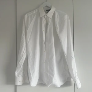 Vit skjorta från Riley  - Klassisk vit skjorta från Riley i regular fit. Skjortan har lång ärm, knappar framtill och stilren krage. Perfekt för dig som gillar en clean och tidlös look. Tillverkad i mjuk bomull som känns skön mot huden.