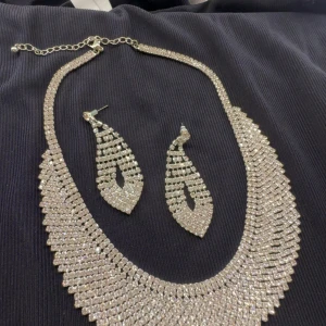 Glittrigt halsband och örhängen set - Säljer ett riktigt snyggt set med halsband och matchande örhängen i glittrande silverfärg. Båda delarna är täckta av små gnistrande stenar som ger en maxad wow-effekt. Perfekt för dig som vill sticka ut och glänsa extra mycket.
