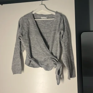 Grå omlottkofta från Even&Odd XS - Mysig grå omlottkofta från Even&Odd i stickad kvalitet. Koftan har långa ärmar, ribbade muddar och knytband i midjan för en snygg passform. Perfekt att slänga på sig när det är lite kyligt ute. aldrig använt str xs