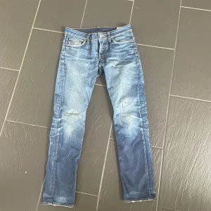 Blå slim jeans från G-Star RAW - Säljer ett par blå jeans från G-Star RAW med snyggt slitna detaljer och ljus tvätt. Jeansen har klassisk femficksdesign, låg midja och smal passform. Materialet är jeans i bomull och de har råa kanter vid bensluten för en cool look.
