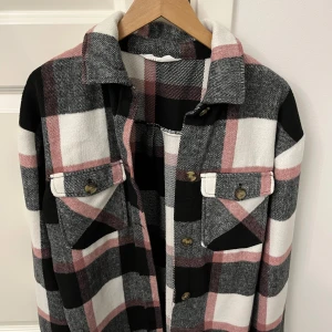 Rutig kappa från H&M - Säljer en snygg rutig kappa från H&M i svart, vit och rosa. Jackan har knappar fram och vid bröstet. 💜