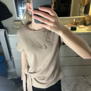 Beige kortärmad topp med knyt - Säljer en stilren beige topp med korta ärmar och en snygg knytning i sidan🩷Perfekt för en avslappnad men chic look. Passar bra till både jeans och kjol💕
