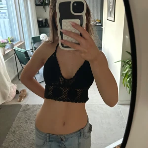 Svart virkad topp - Snygg svart virkad topp med halterneck-design. Perfekt för sommardagar eller en kväll ute. Toppen är croppad och har ett unikt mönster. Aldrig använd och har vaddering på kuporna och är egentligen en one size men passar mig som har storlek S. Pris kan diskuteras💞