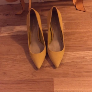 Gula pumps från Aldo - Snygga gula pumps från Aldo med spetsig tå och hög klack. Perfekta för att sätta färg på din outfit. Tillverkade i ett material som ger en elegant look.