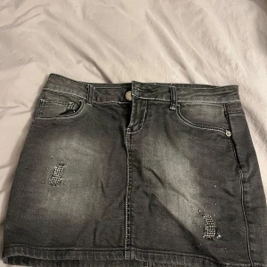 Grå jeanskjol med diamanter  - Snygg grå jeanskjol från Motivi med dekorativa pärlor på fram- och bakfickor. kan sänka priset lite. Köpte i danmark och använt fåtal gånger. För liten för mig och därför säljer jag