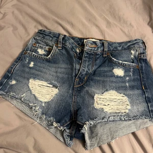 Blå jeansshorts med slitningar - Säljer ett par snygga blå jeansshorts från Gina Tricot som blivit försmå. Storlek 34 nästan aldrig använda