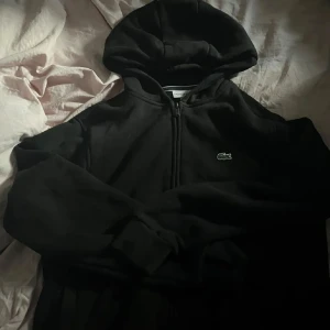 Lacoste hoodie - Lacoste Huvtröja med dragkedja och fickor på sidorna. Storleken är för 165cm (sitter som en S. 
