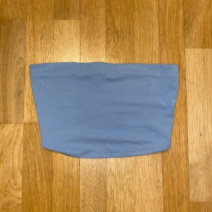 Ljusblå tubtopp - Säljer en stilren ljusblå tubtopp perfekt för sommardagar. Toppen är enkel och smidig att matcha med olika outfits. Perfekt för en avslappnad look eller att klä upp med accessoarer.