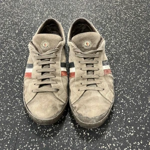 Beige sneakers från Moncler - Biege mocka från moncler, box och påse ingår. Skorna är i slitet skick men går helt klart att både limma själv och gå till skomakare! Priset är DISKUTERBART, vid snabb affär!