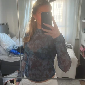 Mönstrad långärmad topp - Säljer en snygg långärmad topp med ett unikt mönster i blå och grå toner. Perfekt för att ge din outfit en cool touch. Toppen har en tight passform och är tillverkad i ett lätt och bekvämt material.