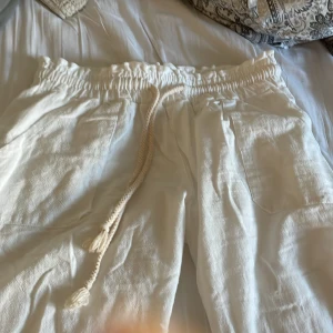 Linnebyxor - Vita linnebyxor. Okänt varumärke. Bra skick men har ett hål på framfickan som syns på bild 4. Fina tunna linnebyxor.