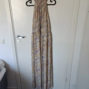 Blommig klänning  - Färgglad, blommig klänning från HM säljes. Storlek 40. Klänningen är delvis öppen i ryggen 