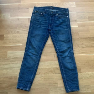 Blå jeans från Polo Ralph Lauren - Snygga blå jeans från Polo Ralph Lauren med klassisk femficksdesign och knappgylf. Jeansen har en normal passform och är tillverkade i denim av hög kvalitet. Perfekta för en stilren look.