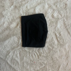 Svart tubtopp - Snygg svart tubtopp som passar perfekt till både jeans och kjol. Den är enkel och stilren, vilket gör den lätt att matcha med olika outfits. Perfekt för en avslappnad dag eller en utekväll.
