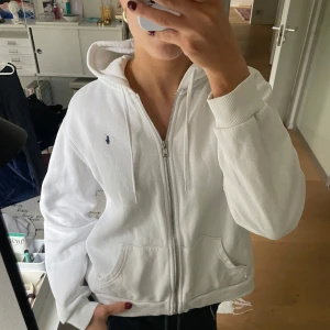 Vit hoodie - Säljer en klassisk vit hoodie från Polo Ralph Lauren. Tröjan har en bekväm passform och är perfekt för en avslappnad stil. Den har långa ärmar och en praktisk huva🥰