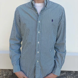Polo Ralph Lauren - Snygg och stilren randig skjorta från Ralph Lauren i grönt och vitt. Skjortan har en slim fit passform och är tillverkad i 100% bomull med stretch. Perfekt för en elegant look.