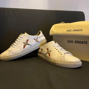 Axel Arigato Clean 90 Bird - Tjena! Säljer dessa snygga vita sneakers från Axel Arigato med broderade fåglar i färgglada nyanser. Ny pris ligger runt 2400kr. Priset kan diskuteras vid snabb affär.