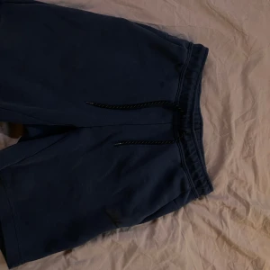 Nike tech shorts - Säljer ett par bekväma blå shorts från Nike med snörning i midjan och praktiska fickor.