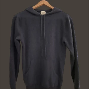 John Henric  - Säljer en stilren mörkblå hoodie med långa ärmar och justerbar dragsko i huvan. Perfekt för en avslappnad look. Passar bra till både jeans och joggers.