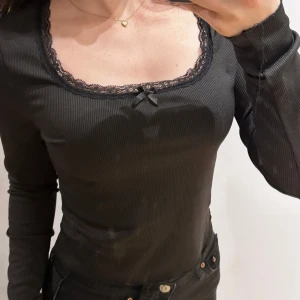 Ribbad tröja från Romwe - Svart ribbad tröja från Romwe med spetsdetaljer och en liten rosett vid halsringningen, tröjan har långa ärmar. 