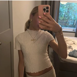 Vit ribbad topp - Säljer en stilren vit ribbad topp med korta ärmar. Toppen har en tight passform och är perfekt för både vardag och festliga tillfällen. Den är enkel att matcha med olika outfits och accessoarer.