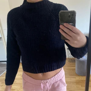 Marin blå stickad croppad tröja - Säljer en marin blå stickad tröja med croppad passform. Tröjan har långa ärmar och en högre krage, perfekt för kyligare dagar. Den är både stilren och bekväm, ett måste i garderoben!