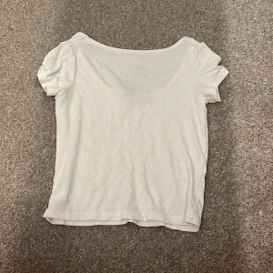 Vit kortärmad topp - Säljer en enkel och stilren vit kortärmad topp.  Toppen har en rund halsringning och är tillverkad i ett mjukt material.