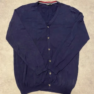 Mörkblå cardigan från Livergy - Säljer en stilren mörkblå cardiganen från Livergy. Den har en v-ringad design med knappar framtill och ribbade muddar vid ärmslut och nederkant. Perfekt för en avslappnad look.