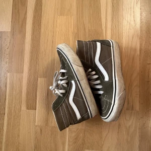 Gröna sneakers från Vans - Säljer ett par gröna Vans sneakers med vit sula och snörning. Skorna har en klassisk hög modell med den ikoniska vita sidoremsan. Perfekta för en avslappnad stil.