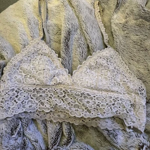 Vit spets bralette/bh - Säljer en vit bralette i spets med blommigt mönster. Den har justerbara axelband, ingen vaddering men det finns hål där man kan lägga in vaddering ifall önskat💗