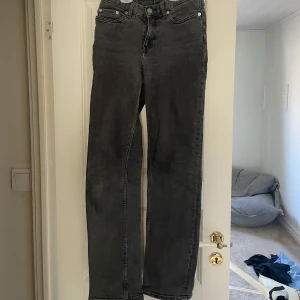 Svarta raka jeans - Säljer ett par svarta jeans med raka ben och klassisk femficksdesign. Jeansen är mid waist och stängs med dragkedja och knapp. Perfekta till vardags och enkla att matcha med olika toppar.