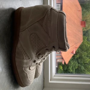 Supersnygga skor 💓💓 - Säljer ett par beige sneakers med kilklack som liknar Isabel marant Bobby sneakers. Mycket bra skick och väldigt efterfrågade!! ❤️❤️ De är från Pavement i stl 38 men jag tycker de sitter mer som stl 39 då de är stora i storleken. 