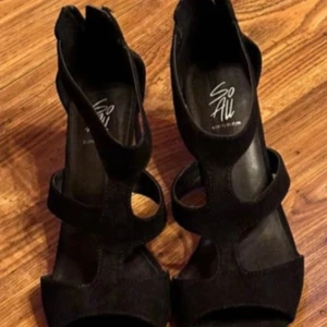 Svarta klackade sandaler med dragkedja - Säljer ett par svarta sandaler med klack från So All. Skorna har öppen tå, breda remmar och dragkedja baktill för enkel påtagning. Perfekta för dig som vill ha en stilren och trendig look.