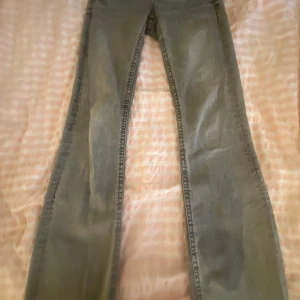 Grå jeansbyxor från Gina Tricot - Grå jeansbyxor från Gina Tricot med raka ben och klassiska fickor fram och bak. Byxorna har knappar och dragkedja framtill samt dekorativa ficklock bak. Perfekta för en avslappnad och stilren look.