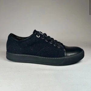 Svarta Lanvins - Säljer ett par helsvarta sneakers med snörning och rund tå. Skorna har en kombination av textil och skinnliknande material på tå och häl. Perfekta för en stilren och enkel look. Storleken är 41 men passar även 42. Pris är ej hugget i sten